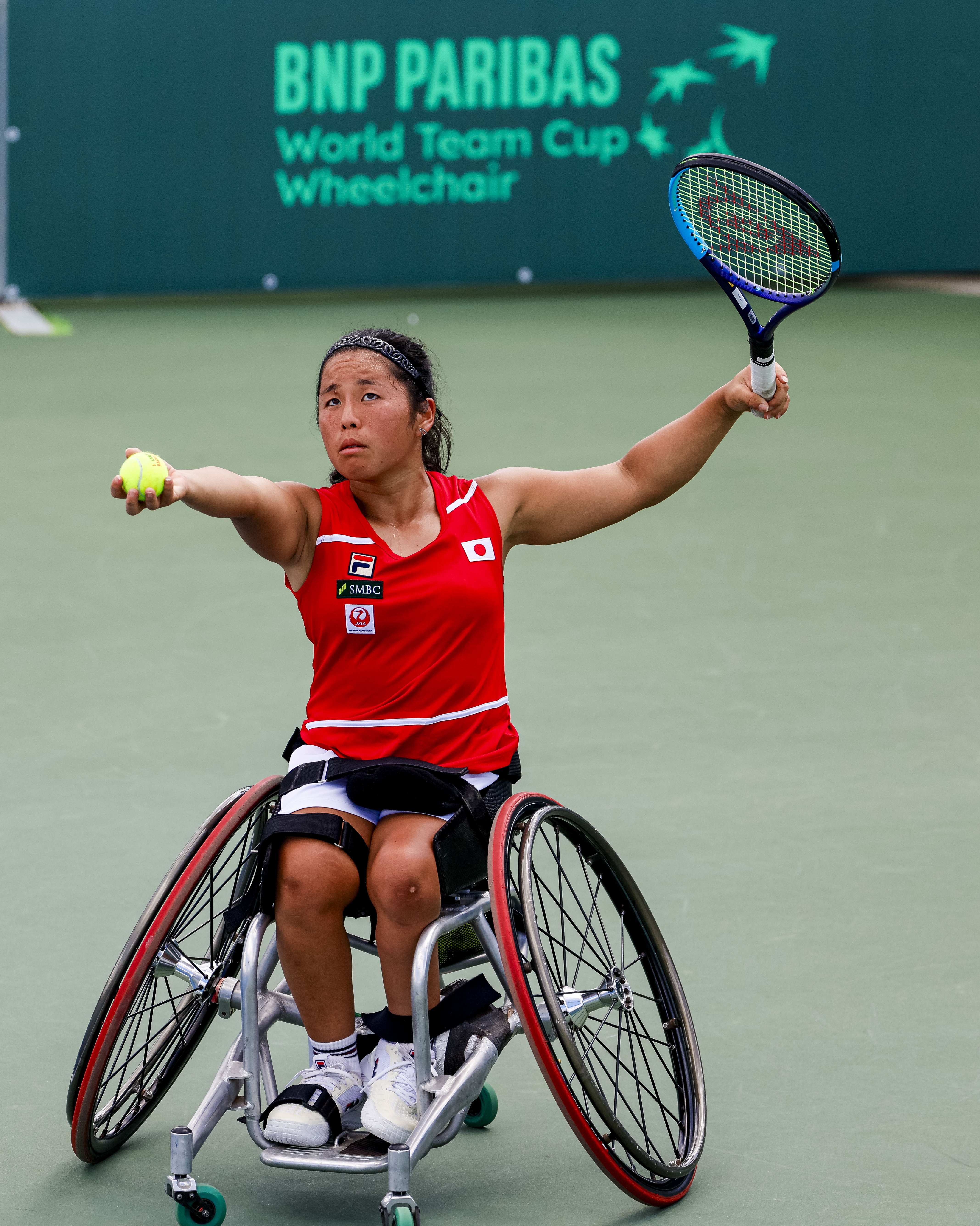 A wheelchair racing athlete in a helmet and racing wheelchair on an athletics track.